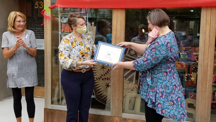 Quilts by Commission Owner Stephanie McCall receives a certificate from CEDA Business Development Specialist Meg Goloub during a grand opening ceremony September 2022.